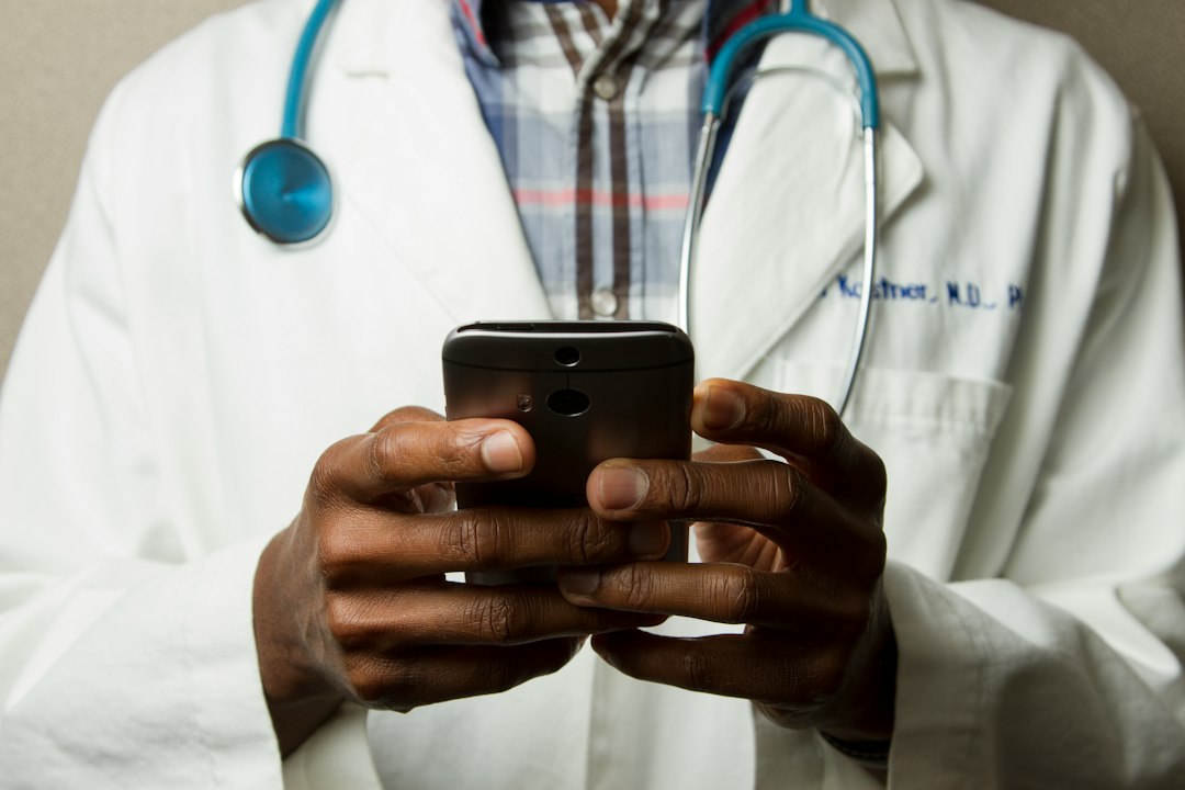 Doctor in a white coat with a stethoscope using a mobile phone